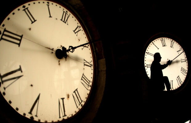 FILE - Custodian Ray Keen inspects a clock face before changing the time on the 100-year-old clock atop the Clay County Courthouse March 8, 2014, in Clay Center, Kan. (AP Photo/Charlie Riedel, File)
