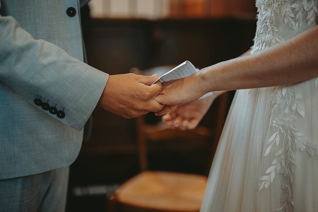 Closeup on a couple's hands exchanging wedding rings during a ceremony.